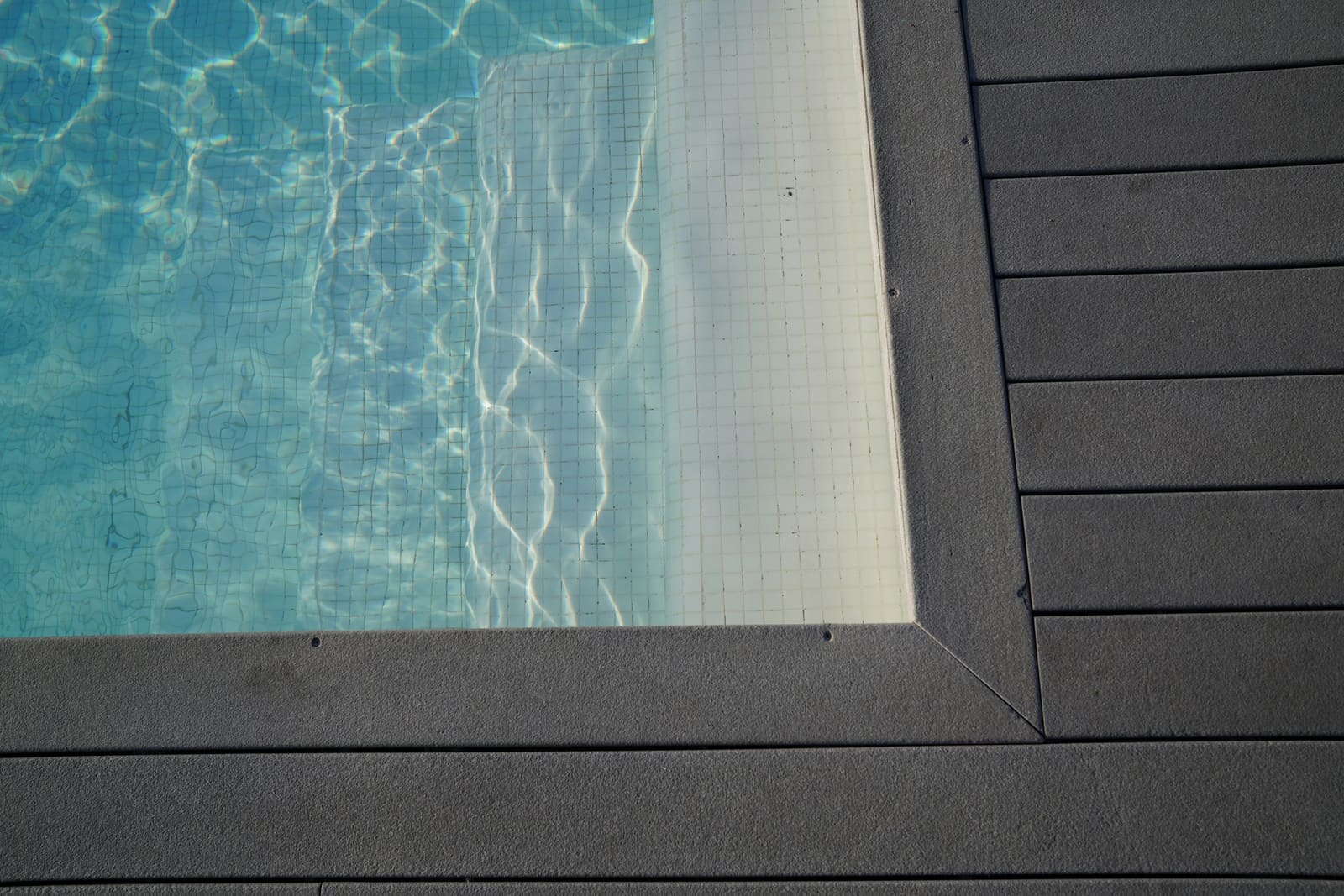 Textured light grey concrete surround bordering a swimming pool