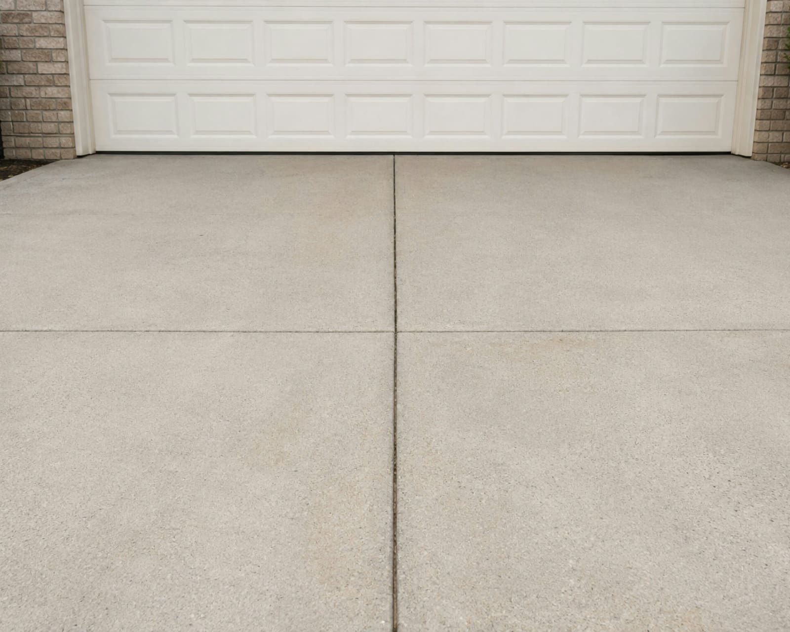 Smooth, freshly finished concrete driveway leading to a garage